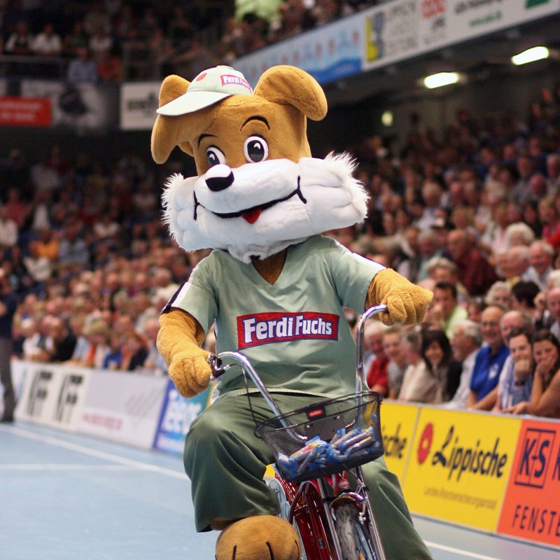 Maskottchen Ferdi Fuchs auf dem Fahrrad in der Halle